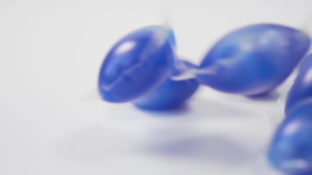 一堆堆透明胶囊 蓝色洗涤剂落在白色背景的特写 透明的聚乙烯泡沫与洗涤剂 慢动作 — 图库视频影像