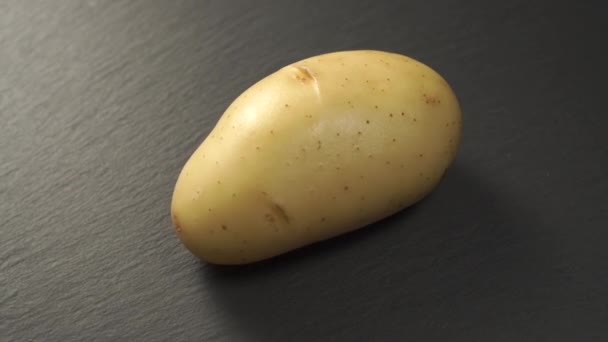 一个未煮熟的土豆在灰色的石头背景上 轮调缓慢 — 图库视频影像