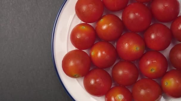 在白盘上的湿樱桃西红柿 在灰色的石头表面上有蓝色的边框 成熟的红色蔬菜 有露水 轮调缓慢 — 图库视频影像