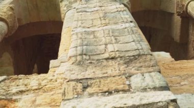 İspanya 'da kemerleri ve desenli sütunları olan eski bir kilisenin cephesi. Antika taş yıkıntısı duvar. Avrupa antik mimarisi. Kamera virajlarla aşağı iniyor