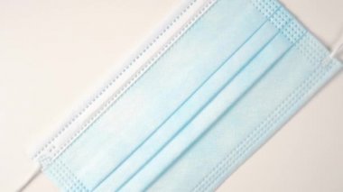 Koruyucu tıbbi maske yakın plan. Doktor tek kullanımlık cerrahi maske takıyor. Mavi ve beyaz. Yavaş dönüş. Coronavirus Önleme Konsepti