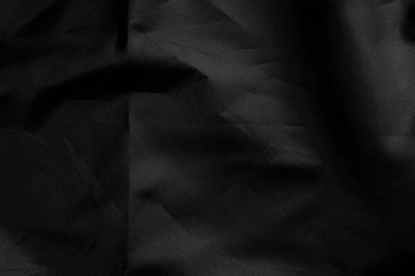 Yüzünde kırışıklıklar ve kıvrık kıvrımlar olan siyah bir madde. Buruşmuş sentetik kumaş. Soyut dramatik arka plan. Tasarım ve başlıklar için.