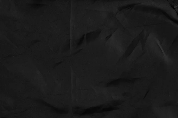 Abstract black synthetic material with wrinkles and wrinkled folds. Old wrapping dusty cloth. Crumpled dramatic texture background. For design and headlines.