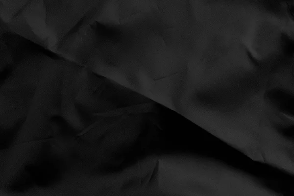 Black wrinkled material with wrinkles and contrasting texture. Dusty packaging. Abstract dramatic background. For design and headlines. Copyspace