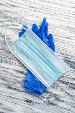 Tıbbi koruyucu maske ve ahşap arka planda nitril mavi eldivenler. Koruyucu hijyen kiti. Coronavirus önleme konsepti. Dikey görünüm