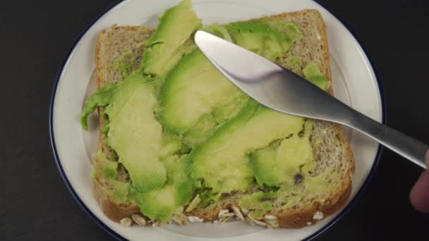 Close Knife Spreads Crumpled Ripe Soft Avocado Piece Cereal Bread — Stock Video
