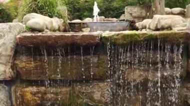 Kahverengi taşlı şelale ve yosunlu bir duvarda su akıntıları. Ağır çekim. Kameranın aşağı doğru hareketi