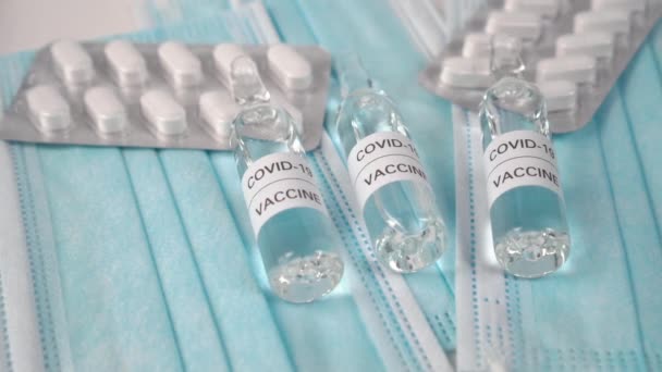 コロナウイルス用の薬のセット 青い医療マスクに白い錠剤とCovid 19ワクチン ウイルス予防と治療の概念 — ストック動画