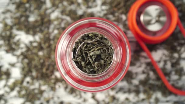 Theelepel voegt gedroogde groene thee bladeren aan de theepot — Stockvideo