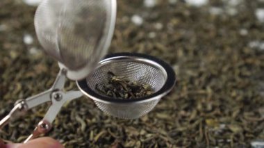 Kurutulmuş yeşil çay yaprakları çay süzgecine düşer. Çin çay töreni.