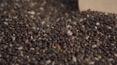 Tahta bir kaşıkta ve bir yığın içinde Chia tohumları. Bir kaşık tohumları yakın plan çeker. Makro çekim