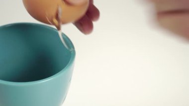 Mavi seramik bardakta tavuk yumurtası kırılır. Tavuk albümleri ve sarı sarısı bir bardağa akıyor. Parçalar kenarda duruyor. Doğal ve sağlıklı malzemeler kullanarak yemek hazırlıyorum.