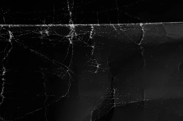 Eski püskü, katlanmış, toz ve kırışıklıklarla kaplı siyah kağıt yüzeyi.