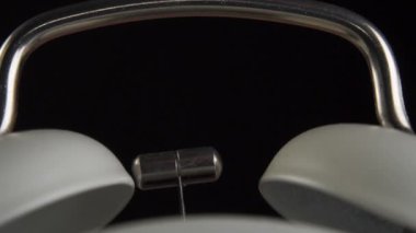 Eski usul çalar saat, siyah arka planda gümüş çekiçle yakın plan çanları çalar. Makro atış. Yavaş çekim