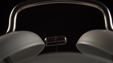 Siyah arka planda, çanlar ve gümüş bir çekiçle yakın plan üzerinde klasik beyaz alarm saati. Makro çekim