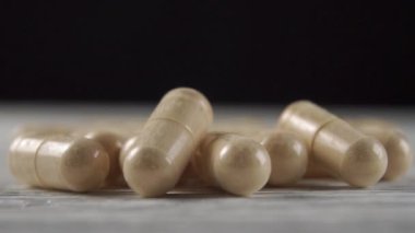 Ahşap bir arka planda bej bitkisel tıbbi kapsüller. Makro dolly çekimi