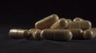 Siyah bir yüzeye yığılmış tıbbi kapsüller. Alternatif tıp ve bitkisel tedavi kavramı