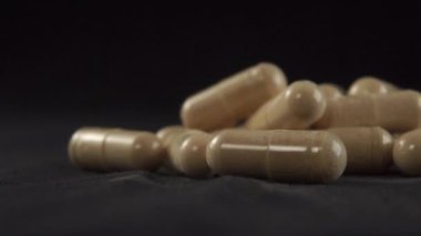 Siyah bir yüzeye yakın tıbbi homeopatik kapsüller. Makro atış. Doğal bitkisel malzemeler ve takviyelerle alternatif tıp konsepti