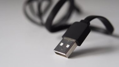 Beyaz bir masa üzerinde siyah kabloyla Usb prizi. Makro dolly çekimi
