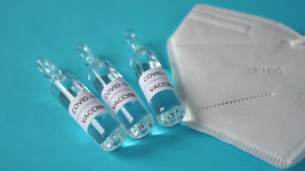 Covid 19青色の表面にアンプルおよび呼吸器医療マスク中のコロナウイルスワクチン コロナウイルス感染の予防 予防接種および治療のために — ストック動画