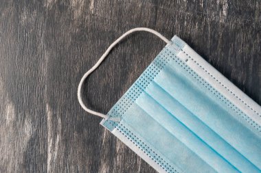 Virüsün yakın planda tutulması için tahta bir arka planda tıbbi maske.