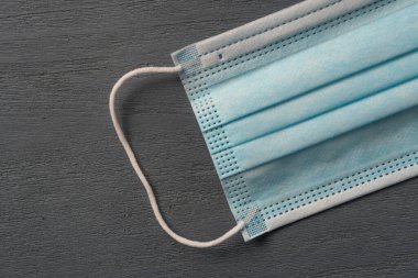 Virüsün yakın planda tutulması için tahta bir arka planda tıbbi maske.