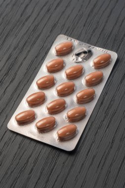 Kahverengi haplar gümüş bir su toplayıcı paketinde koyu, tahta, gri bir dokuya yakın