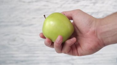 Yeşil elma ahşap arka planda el ele.