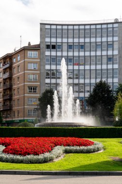 Oviedo, İspanya, Asturias - Ağustos 2020: Gökyüzü ve binaların zeminine karşı bir çeşme, güzel çiçekler ve bitki örtüsü olan meydan. Şehir manzarası. Oviedo. İspanya. Asturyalar