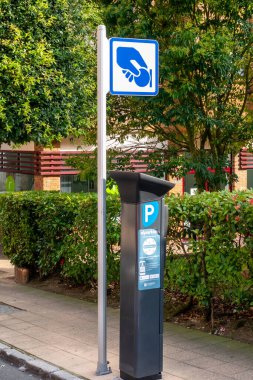 Oviedo, İspanya, Asturias - Ağustos 2020: Bozuk para tutan eli sembolize eden mavi işaretli ödeme makinesi. İspanya 'nın kuzeyindeki Oviedo şehrinin Asturias caddesinde.