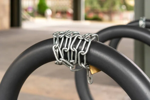Chain lock for bike safety in the bike parking with gray iron rings. Lifestyle and safety concept