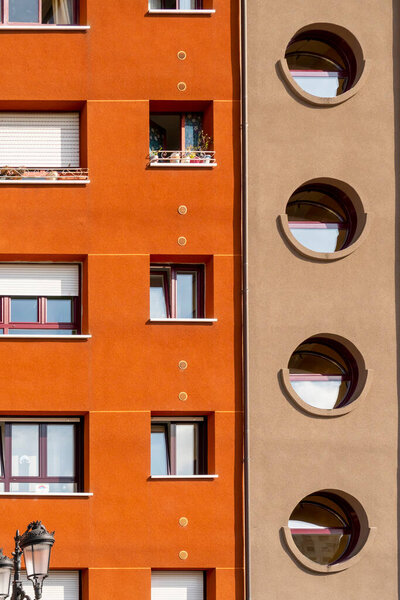 Oviedo, Spain, Asturias - August 2020: Bright facade of a residential building. Geometric shapes. Rectangular and round windows. Abstract concept