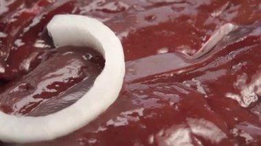 Beyaz soğan parçaları pişmemiş dana ciğerin üzerine düşer. Makro çekim. Yavaş dönüş. Et yemeği pişirmek. Seçici odak