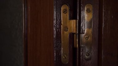Kaliteli ahşap kapaklı bir kapıyı kapatıyorum. Bronz menteşe yakın çekim. Işığın ve gölgenin yansımalarının oyunu