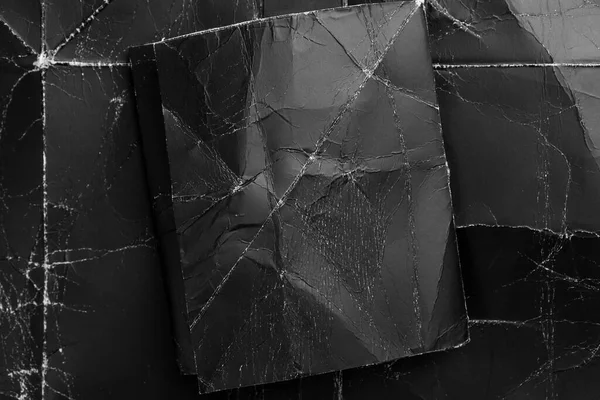 Siyah, pejmürde bir arkaplan üzerine buruşuk kağıt. Koyu kağıt tasarım için hazırlanır. Dramatik bir arka planda katlanmış bir sayfa. Eski model.
