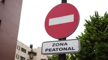 Sokak binaları, ağaçlar ve gökyüzünün zeminine karşı İspanyolca ve giriş yasaklanmış Pediatri Alanı tabelası. Giriş yasak. Yakın plan.