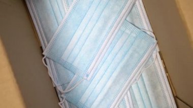 Karton bir nakliye kutusunda tıbbi koruyucu maskeler. Kahverengi ambalajlı büyük parti maskeler. Koronavirüs salgını ve COVID-19 'a karşı korunma için sevk