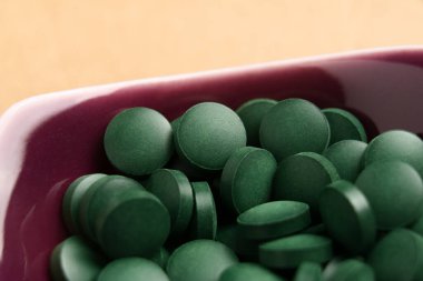 Seramik bir kapta yeşil spirulina tabletleri. Algler için detoks takviyesi. Makro