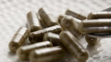 Beyaz seramik arka planda bitkisel kapsüller. Alternatif ilaç takviyeleri