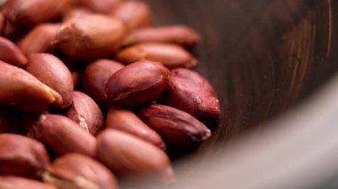 Kahverengi tenli kavrulmuş fıstık, ahşap bir kasede düzenlenmiş. Makro. Döndürme