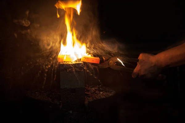 Unerkennbare Hände des Schmieds bereiten Metall auf Amboss für das Schmieden mit Feuer vor — Stockfoto