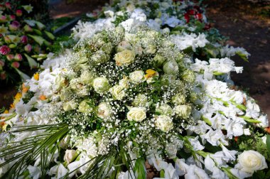 Festive elegant grave decoration made of cream-colored roses nestled in gypsophila and lined with white gladioli