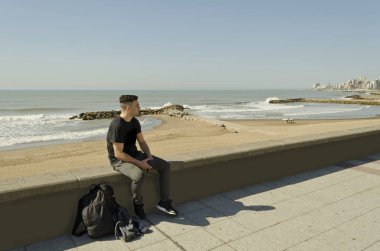 güneşli bir günde kumsalda yürüyen genç adam