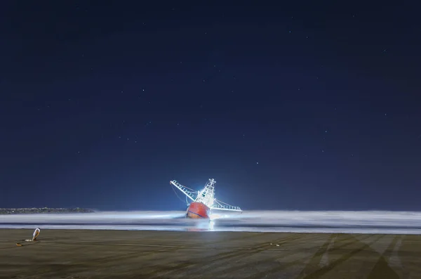 Fishing boat stranded on the beach in the long night exposure