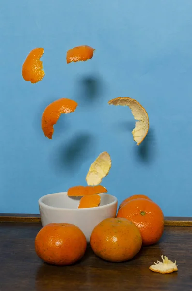 Tangerinas Cascas Caindo Uma Tigela Branca Fundo Azul Claro Movimento — Fotografia de Stock