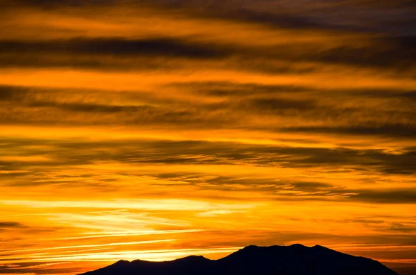Karlı Dağlar Bulutlu Günbatımı Gökyüzünün Altında Görünür — Stok fotoğraf