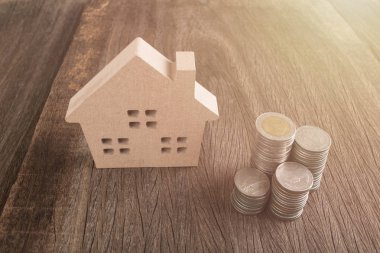 Yükselen madeni paralar ve arka planda bir ev