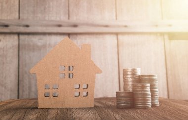 Yükselen madeni paralar ve arka planda bir ev