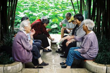 Xi'an / Çin - 24 Haziran 2011: oyun kartları ve küçük gölet yanındaki bir parkta sohbet kadın ve yaşlı Çinli adam