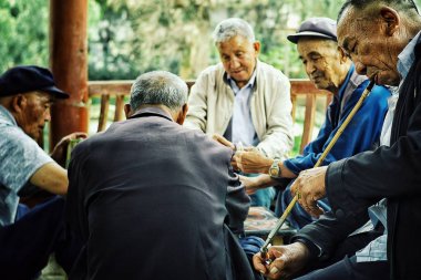 Beijing / China - 24 Haziran 2011: yaşlı Çinli adam uzun bambu boru filtre ile puro onlardan biri sırasında bir parkta oyun kartları